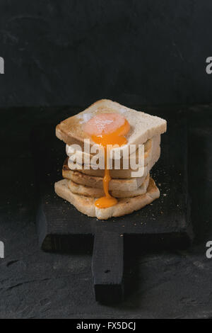 Toast mit Eigelb über schwarz Stockfoto