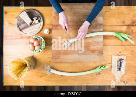 Die Carbonara Pasta vorbereiten.  Weibliche Hände den Lauch vorbereiten. Stockfoto