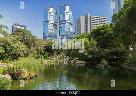 Blick auf Teich an der üppigen Hong Kong Park und Lippo Centre Wolkenkratzer dahinter in Hong Kong, China. Stockfoto