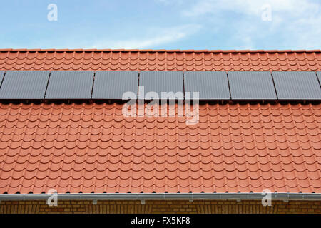 Solar thermische Flachkollektoren auf einem roten Ziegeldach Stockfoto