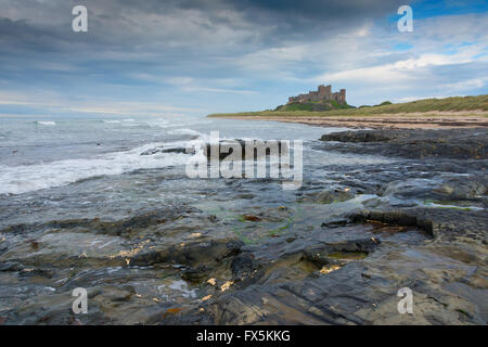 Bamburgh Castle in der Abenddämmerung entlang der Küste England aus der Ferne betrachtet Stockfoto