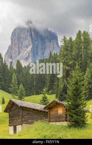 Mount Langkofel in der Langkofel Bergkette mit kleinen Kabinen vor, Wolken oben, Selva, Val Gardena, Ital Stockfoto