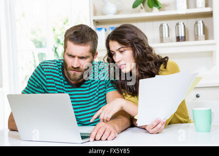 Paar, die Bezahlung ihrer Rechnungen mit Laptop in Küche Stockfoto