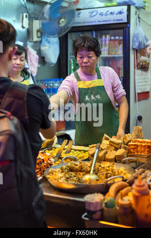 Frau verkaufen verschiedene Lebensmittel in Kowloon, Hong Kong, China. Stockfoto