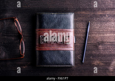 Bibel, Brillen und Stift auf alten Holztisch gelegt Stockfoto