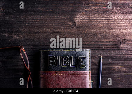 Bibel, Brillen und Stift auf alten Holztisch gelegt Stockfoto