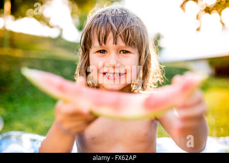 Niedliche kleine Mädchen essen Wassermelone in sonniger Sommergarten Stockfoto