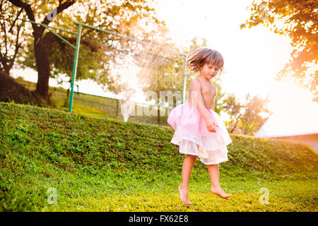 Mädchen in Prinzessin Rock im sonnigen Garten springen Stockfoto