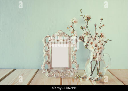 Vintage-leere Rahmen neben weißen Frühlingsblumen. selektiven Fokus. Vorlage, bereit, Fotografie. Jahrgang gefiltert Stockfoto