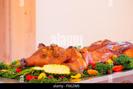 Ganzes Schwein bei einer Hochzeitsfeier mit einem Apfel im Maul auf einem Tisch. Stockfoto