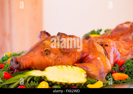 Ganzes Schwein bei einer Hochzeitsfeier mit einem Apfel im Maul auf einem Tisch. Stockfoto