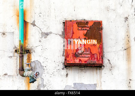 Fire-Fighter-Box für Feuer-Schlauch und Ventil auf einer verwitterten Mauer des alten Gebäudes Stockfoto