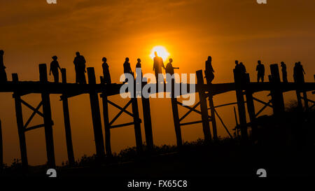 Eine Gruppe von Menschen, die über die hölzerne U-Bein Brücke, Amarapura Township, bei Sonnenuntergang. Stockfoto