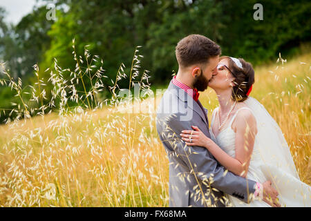 Braut und Bräutigam küssen in einem Feld am Tag ihrer Hochzeit. Stockfoto