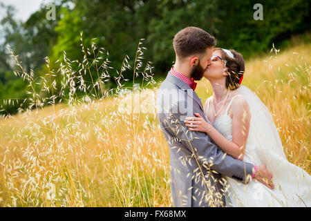 Braut und Bräutigam küssen in einem Feld am Tag ihrer Hochzeit. Stockfoto