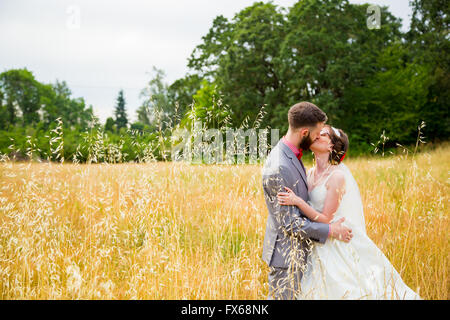 Braut und Bräutigam küssen in einem Feld am Tag ihrer Hochzeit. Stockfoto