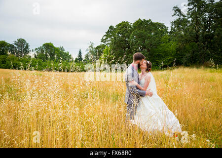 Braut und Bräutigam küssen in einem Feld am Tag ihrer Hochzeit. Stockfoto