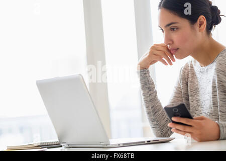 Hispanic Frau mit Handy und laptop Stockfoto