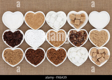 Braunen und weißen Zucker Auswahl im Herzen geformte Schalen über hessische Hintergrund. Stockfoto