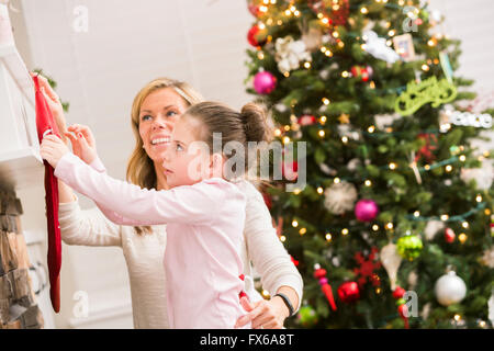 Kaukasische Mutter und Tochter hängende Weihnachtsstrümpfe Stockfoto