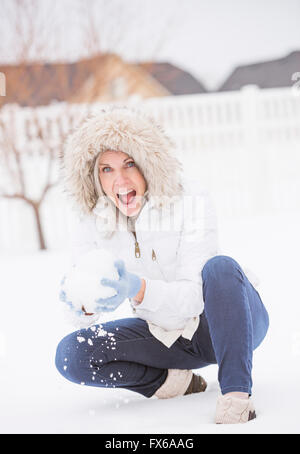 Kaukasische Frau werfen Schneeball im Schnee Stockfoto