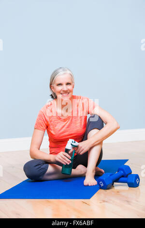 Kaukasische Frau Trinkwasser auf Yoga-Matte Stockfoto