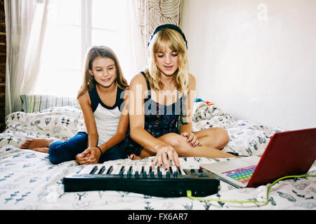 Schwestern spielen Tastatur auf Bett Stockfoto