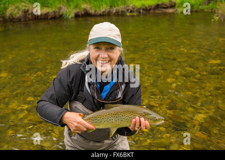 Kaukasische Frau mit Fisch in abgelegenen Fluss Stockfoto