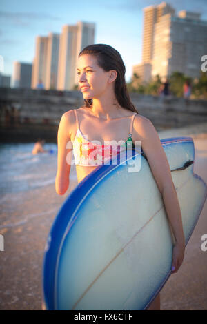 Gemischte Rassen Amputierte Surfbrett am Strand tragen Stockfoto