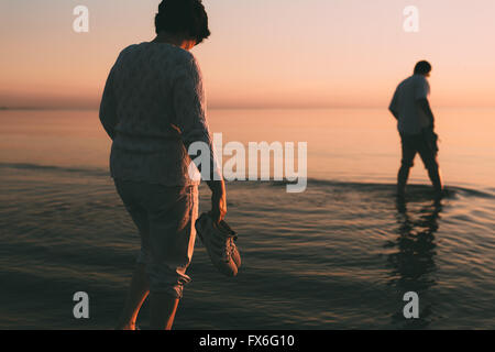 Erwachsenen verheiratetes Paar Schuhe in der hand hält und Spaziergänge am Wasser. Stockfoto