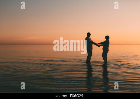 Silhouette eines erwachsenes paar stehen im Meer vor einem Sonnenuntergang. Stockfoto