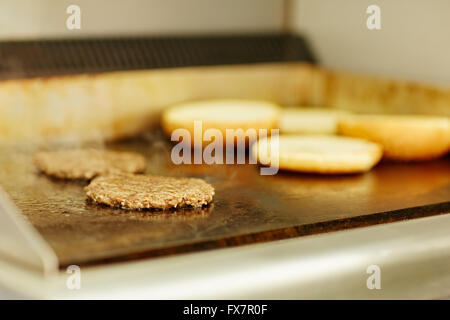 Burger Bratlinge gebraten neben offenen gerösteten Brötchen Stockfoto