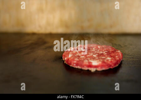 Hamburger Patty mit Gewürz-brutzeln auf dem grill Stockfoto