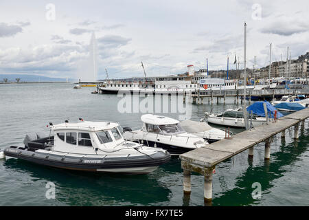 Kleine Boote vertäut am Steg vor der Promenade du Lac mit Wasserstrahl Brunnen im Hintergrund, Genf Stockfoto