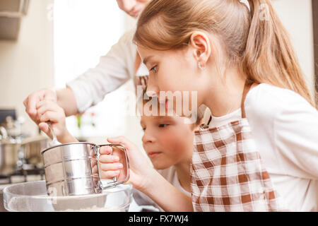 Familie kochen Hintergrund. Mutter und Kinder in der Küche Siebung Mehl Stockfoto