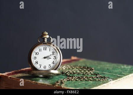 Nahaufnahme von Vintage Taschenuhr auf altes Buch vor einem dunklen Hintergrund Stockfoto