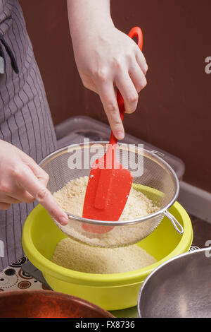 Händen siebt Mehl in Schüssel zum Backen von Kuchen Stockfoto