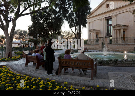 Einheimische und Touristen-Mühle ungefähr an der historischen Upper Barakka Gardens in Valletta in der Dämmerung. Stockfoto