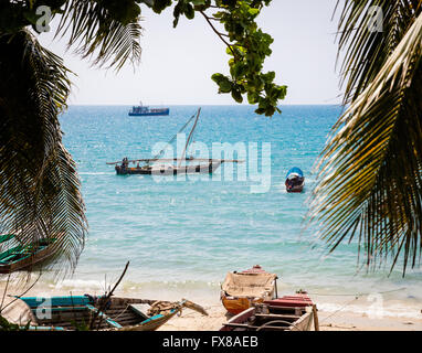 Strand in der Altstadt von Stone Town Sansibar mit Fischerbooten und einem Segel-weniger Dhow durch Harbourside Bäume gesehen Stockfoto