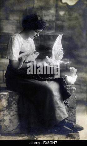 Deutschland - ca. 19100: Postkarte gedruckt in der Deutschland zeigt Frau sitzen auf Steinstufen, weiße Tauben füttern Stockfoto