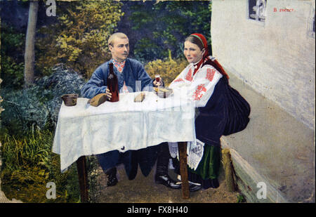 Postkarte gedruckt in Russland zeigt Mann und Frau in der ukrainischen nationalen Kleidung, die am Tisch sitzen - ein Mann gibt der Frau ein Glas Wein Stockfoto