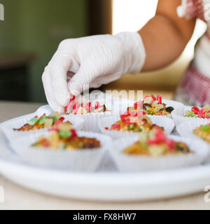 Junge Frau legt kandierte Früchten auf den Kuchen in der Küche Stockfoto