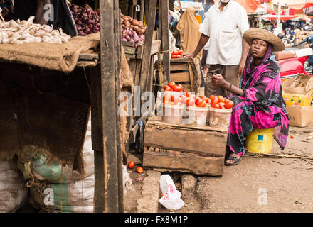 Afrikanische Frau, die traditionelle Kleidung verkaufen Tomaten in einem lokalen Markt. Stockfoto