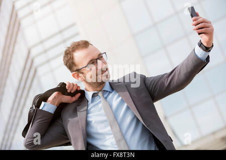 Glücklich Kaufmann mit einer Tasche über der Schulter nehmen Selfie im freien Stockfoto