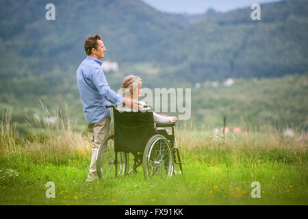 Ältere Mann mit Frau im Rollstuhl, grün Herbst Natur Stockfoto