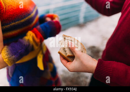 Hand des Mannes hält eine Scheibe Brot ganze Weat. Meer Hintergrund. Kreativkonzept Stockfoto