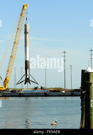 Port Canaveral, Florida, USA. 12. April 2016. Die erste Stufe einer SpaceX Falcon 9 Rakete wird mit einem Kran in Port Canaveral, Florida nach Rückkehr in den Hafen über Nacht auf einem Lastkahn Drohne gehisst. Die Rakete erfolgreich gelandet auf dem Kahn zum ersten Mal am 8. April 2016 nach dem Start von Cape Canaveral mit einer Dragon-Raumschiff auf einer Mission, Nachschub für die ISS. SpaceX hofft, die Rakete in den kommenden Monaten wieder verwenden. Bildnachweis: Paul Hennessy/Alamy Live-Nachrichten Stockfoto