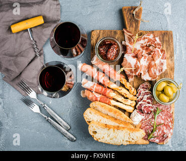 Auswahl an Fleisch-Vorspeise. Salami, Schinken, Brot-Sticks, Baguette, Oliven und getrockneten Tomaten, zwei Gläser rote Wein ove Stockfoto