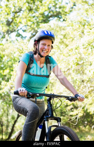 Reife Frau lächelnd und Fahrrad fahren Stockfoto