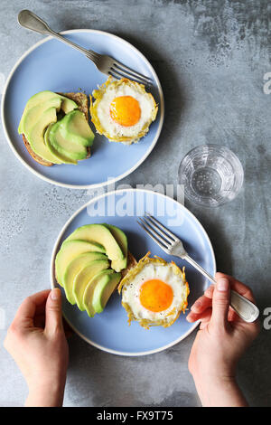 Gebackenen Eiern in Kartoffel Nester mit Avocado-toast Stockfoto